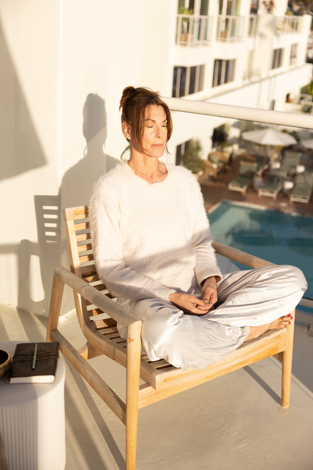 Alicia Gilbert meditating in warm sunlight on a balcony